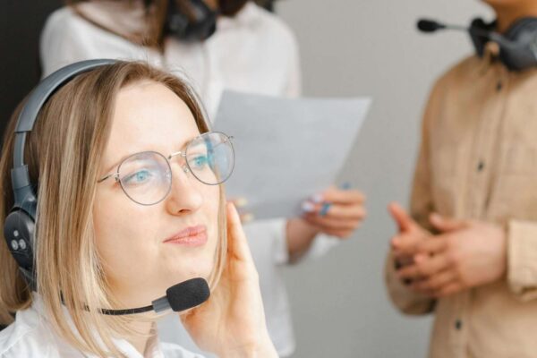 Team of professionals in a call center discussing customer service strategies while wearing headsets.