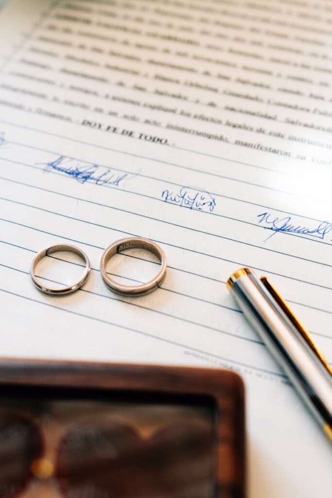 Elegant wedding rings laid on a signed marriage certificate, symbolizing commitment.